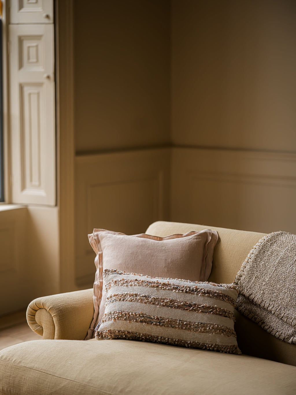 Brancaster woven lumbar cushion in chestnut styled on a sofa