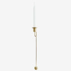 Gold candle holder with a white candle on a white background