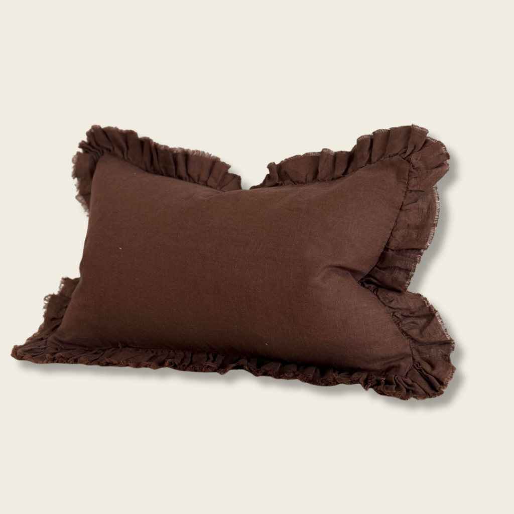 brown linen cushion with ruffle edges on a beige background