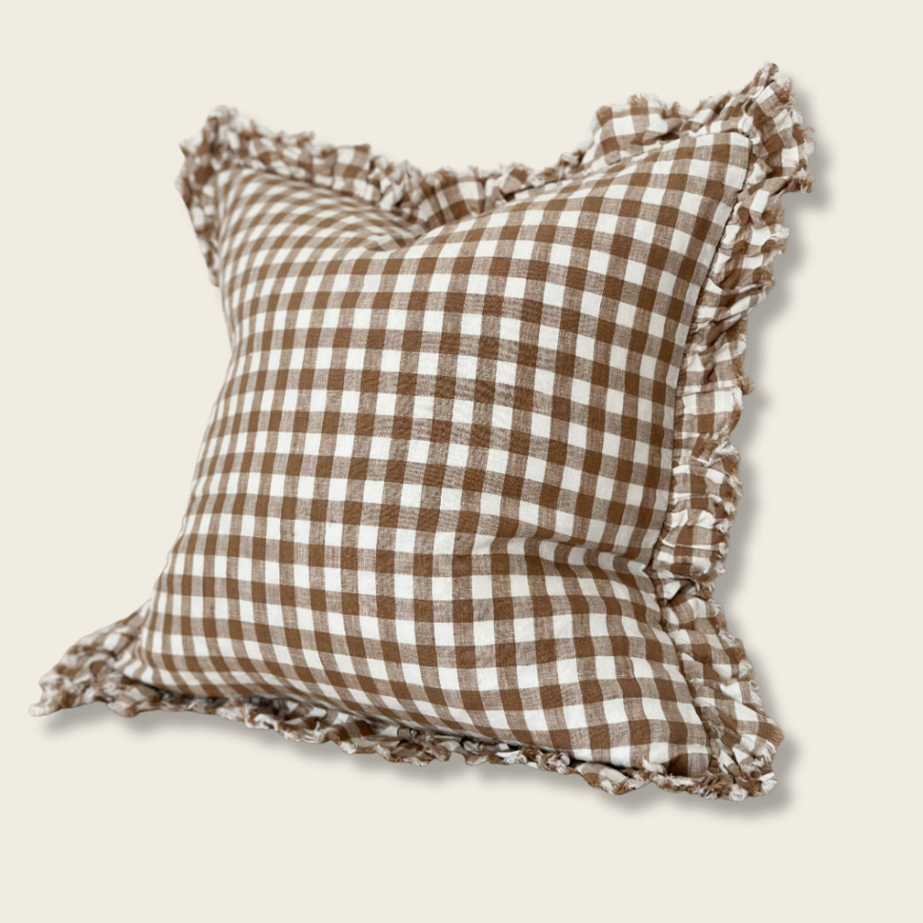 Brown and white checkered pillow with ruffled edges on a beige background