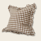 Brown and white checkered pillow with ruffled edges on a beige background