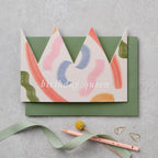 Brushstroke paper crown birthday card shown worn as a crown