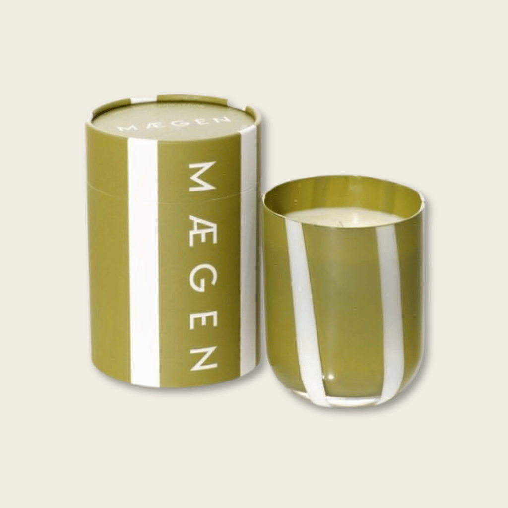 Green candle in a matching container with 'Mégen' branding on a beige background