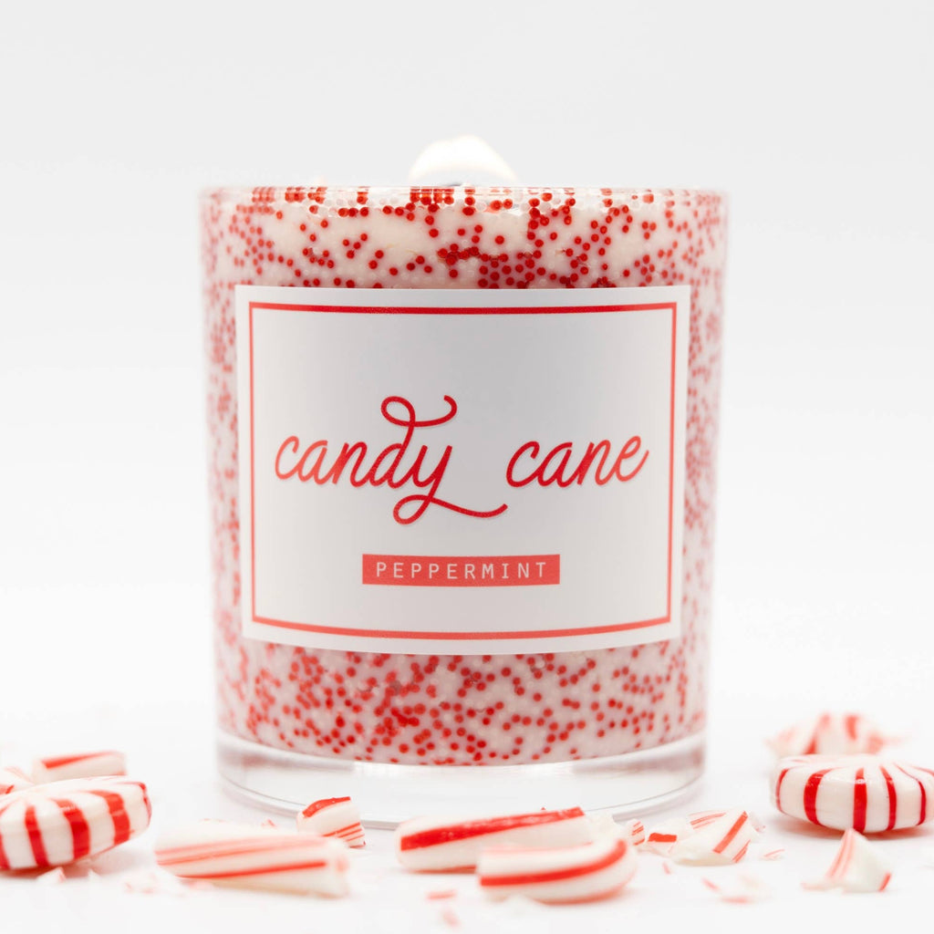 Candle labeled 'candy cane' with red and white speckles, surrounded by candy canes on a white background.