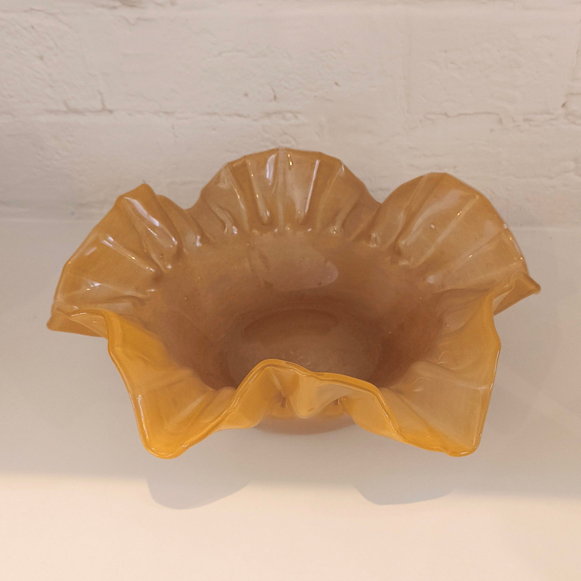 Caramel glass bowl on a white surface with a light gray background