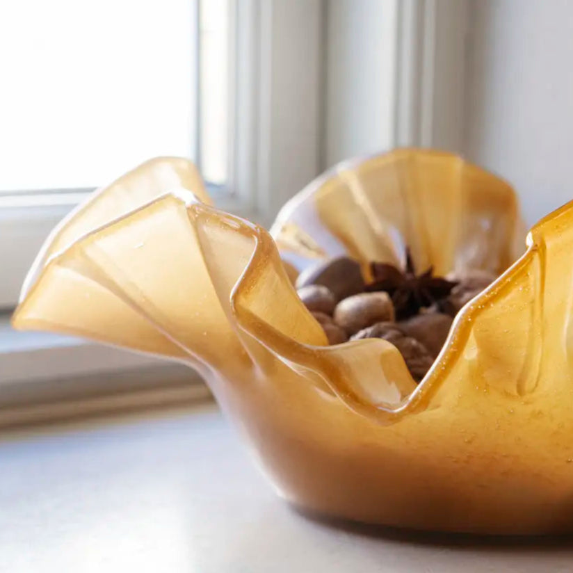 Gold decorative bowl on a white surface with a blurred window background