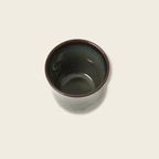Ceramic cup with brown rim on a light beige background