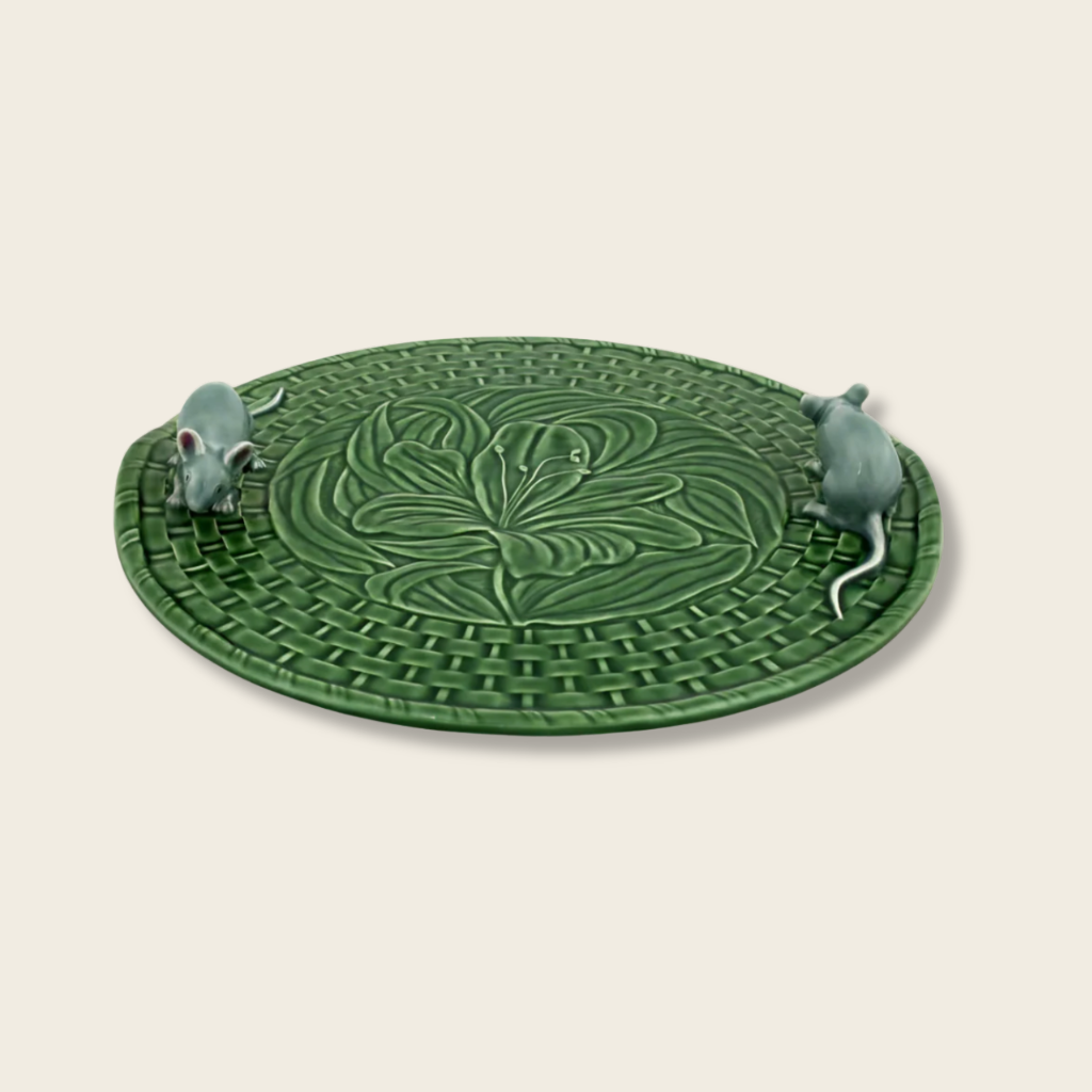 Green ceramic trivet with decorative design and two small mice figures on a beige background