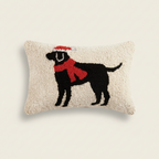 Decorative pillow with a black dog silhouette wearing a red scarf and Santa hat on a beige background.
