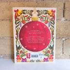 Christmas-themed product packaging with a red ball and festive decorations on a white surface.