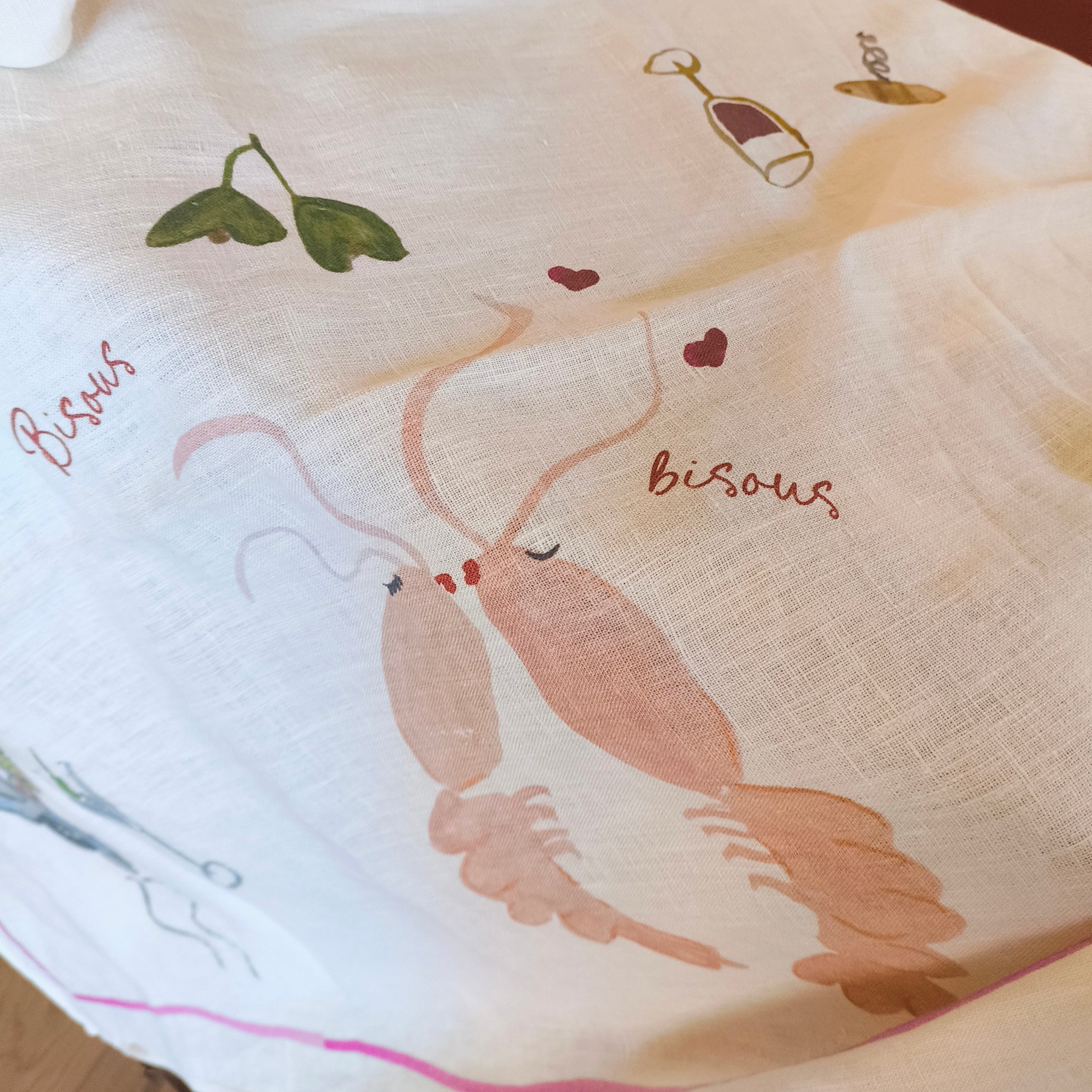 table cloth with designs of lobsters and 'bisous' text on a wooden surface.