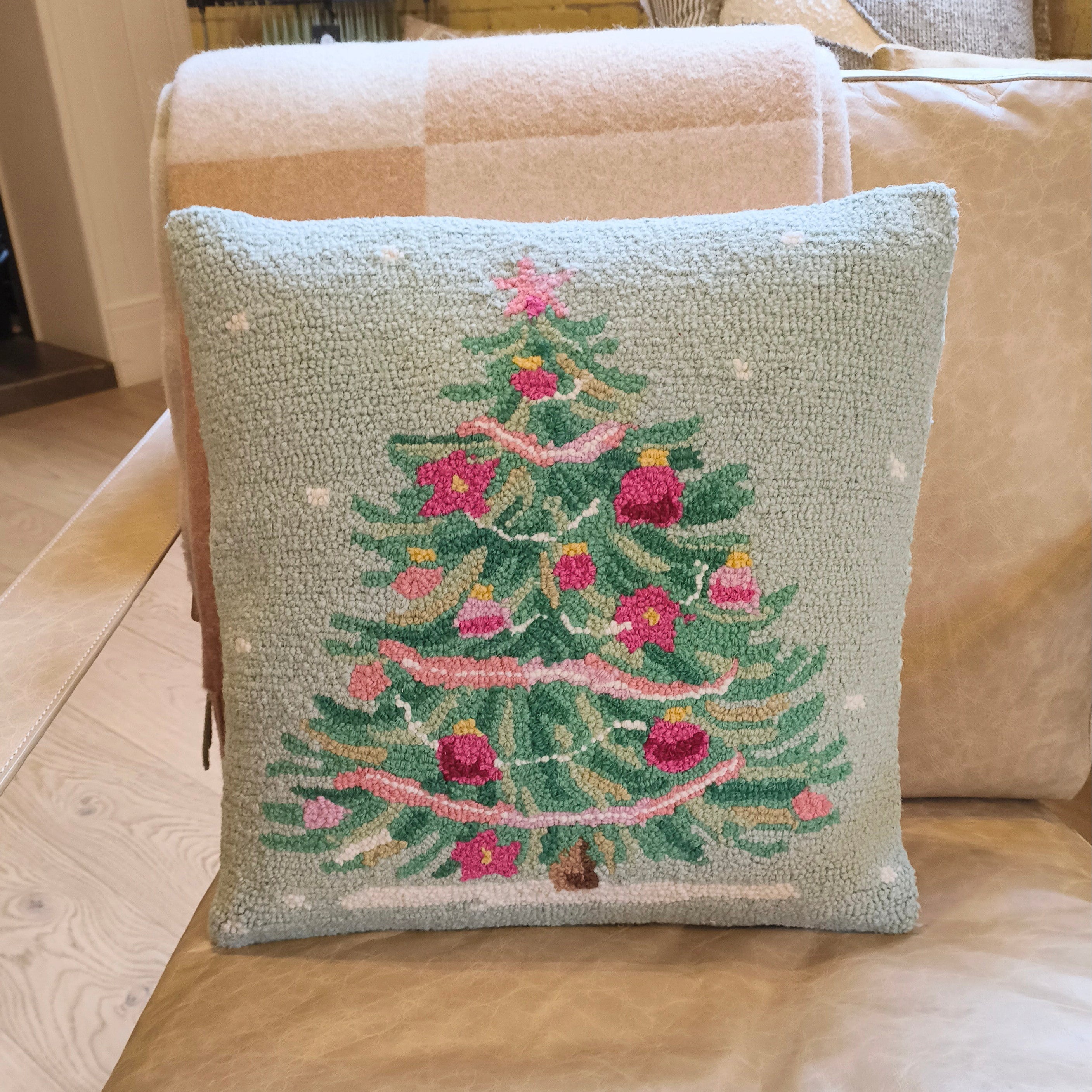 Decorative pillow with a Christmas tree design on a beige sofa.