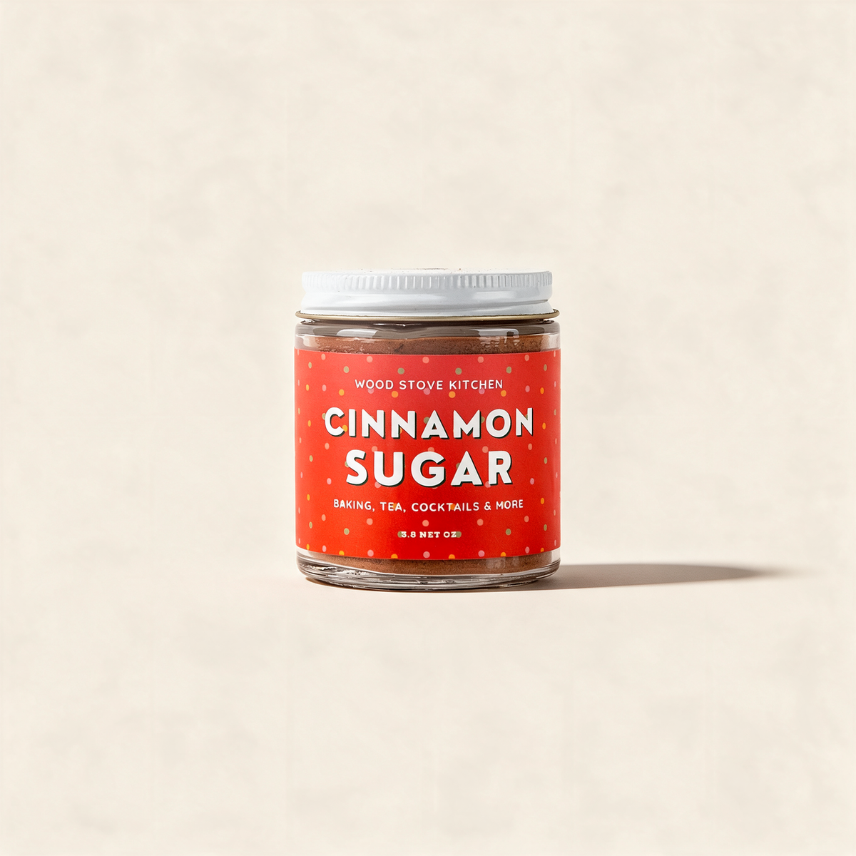 Cinnamon sugar in a clear glass jar with a white lid on a warm cream background