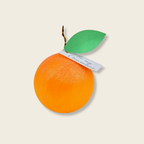 Orange-shaped suprise ball with a green leaf and white label on a beige background