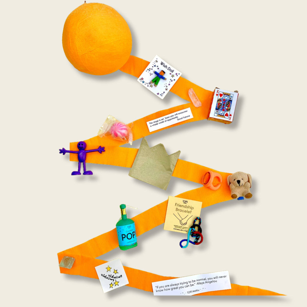 party favour game setup with cards, toys, and an orange on a beige background