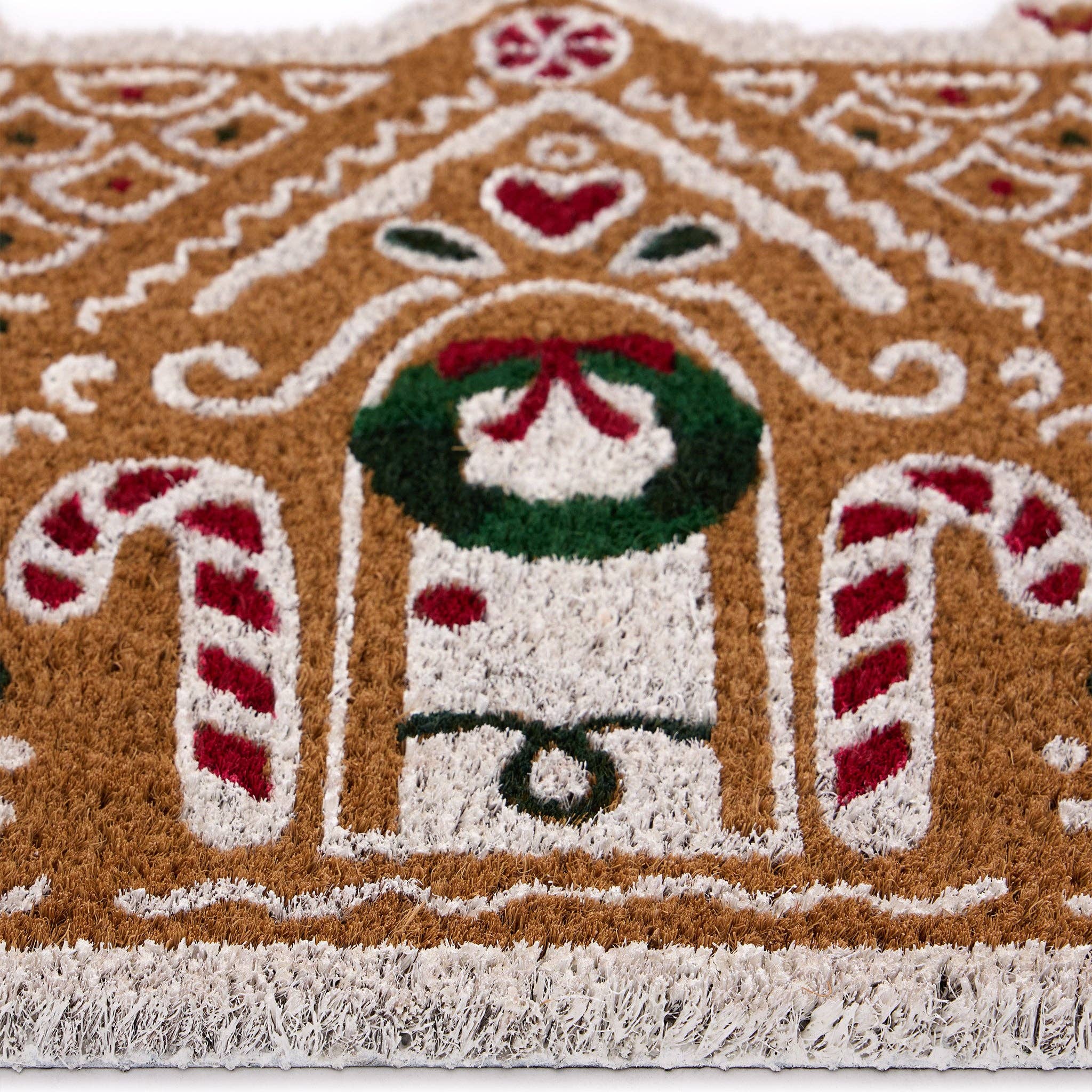Decorative doormat with gingerbread house design featuring a snowman, candy canes, and a wreath.