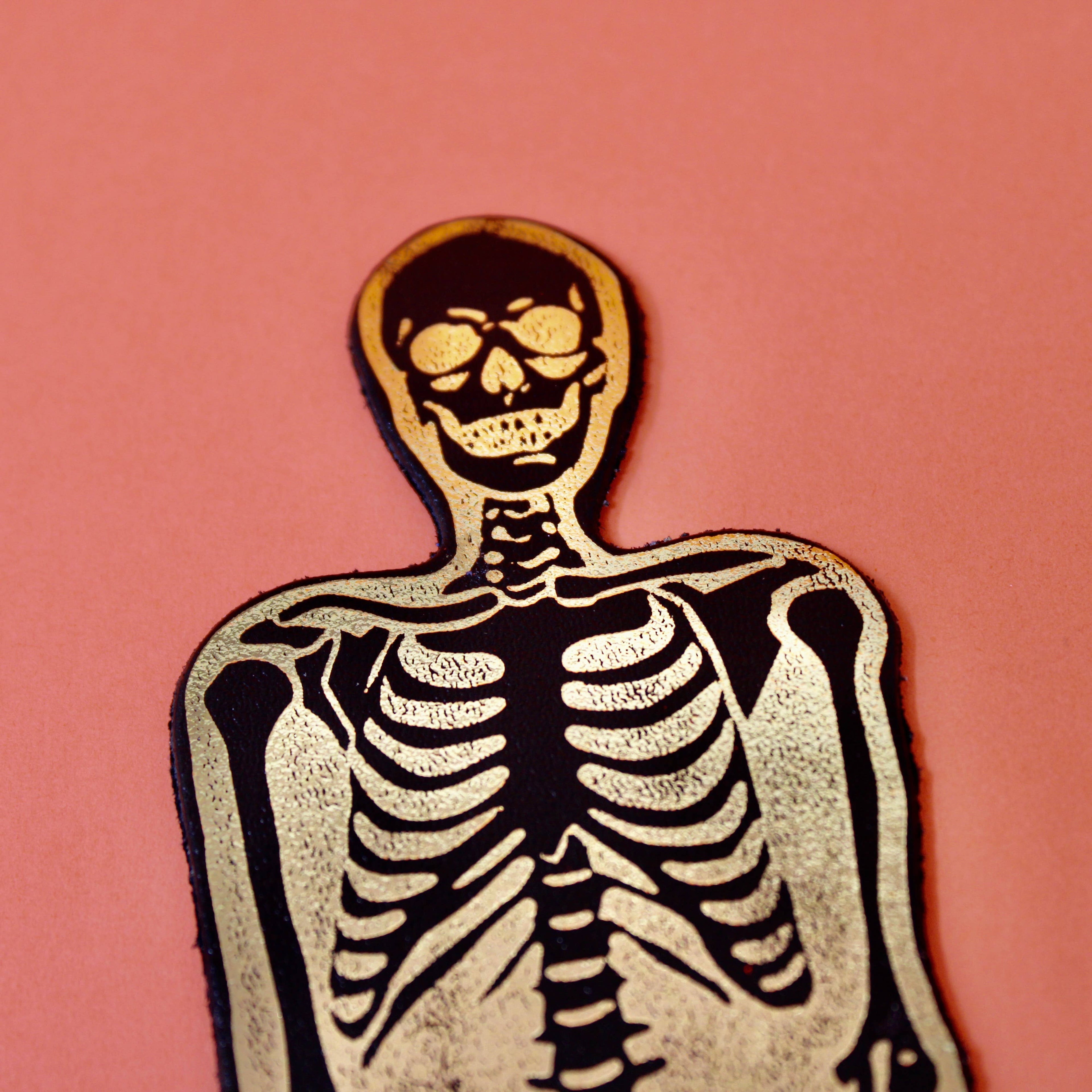 gold foil skeleton bookmark on a pink background.
