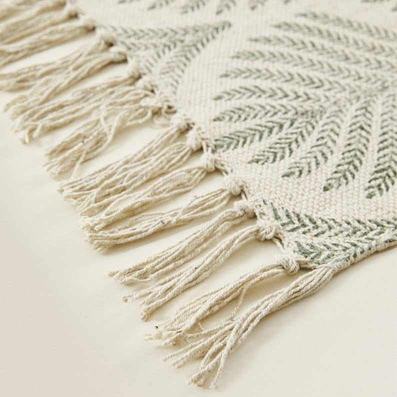 Close-up of a textured rug with fringe on a light background