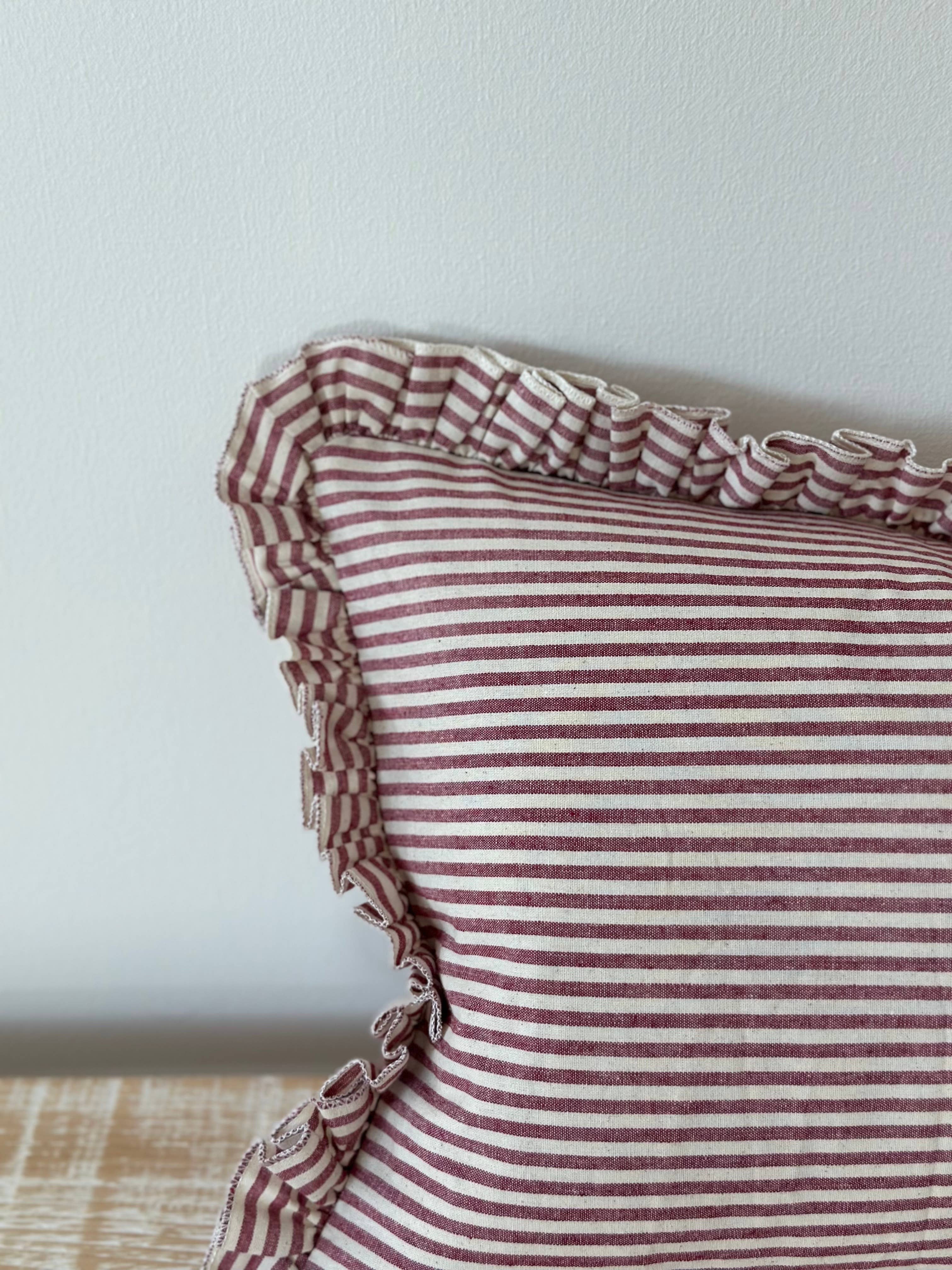 Detail of the burgundy stripe and ruffle trim on the Darcy cushion cover