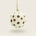 Decorative egg-shaped ornament with brown polka dots on a white background