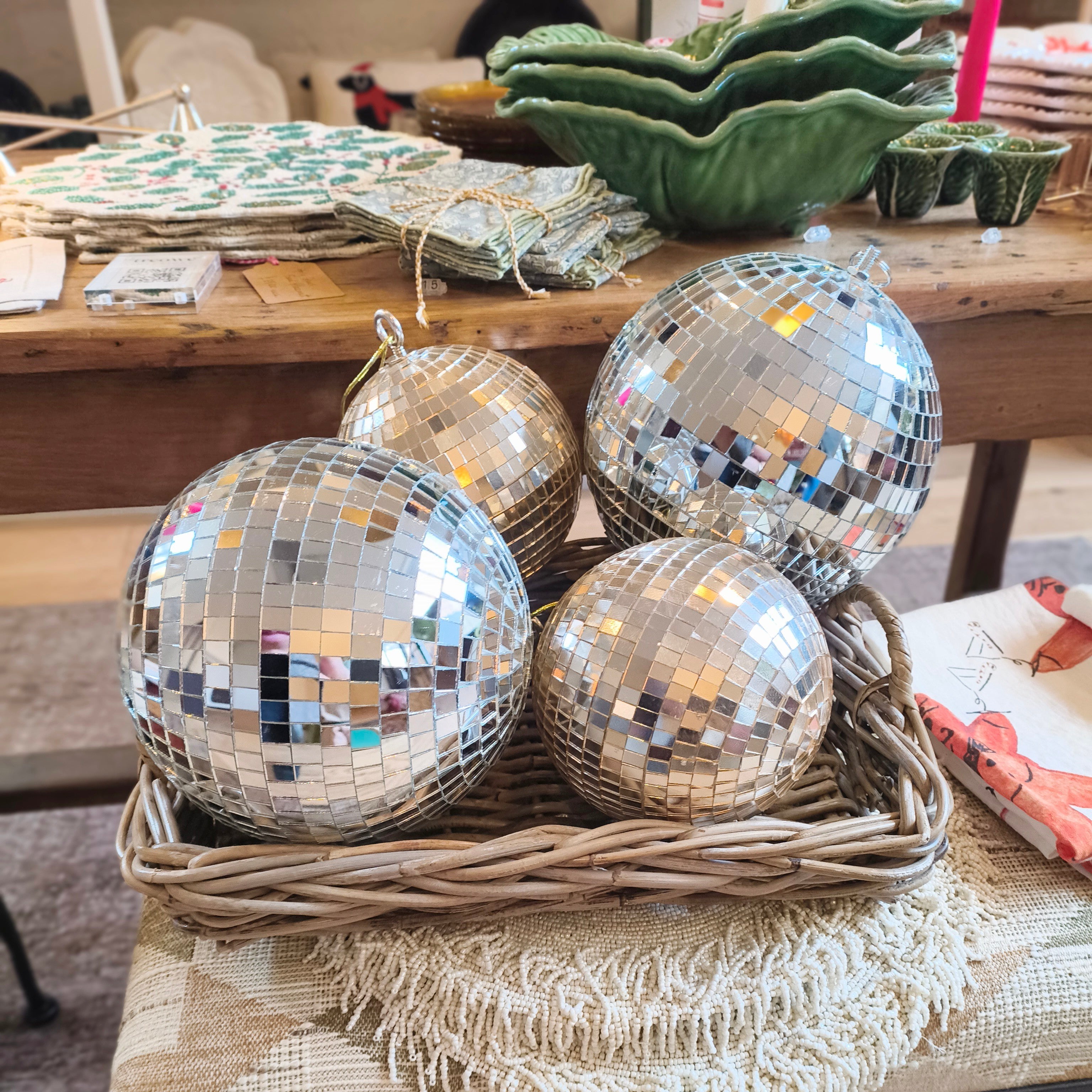 Silver disco balls in a woven basket on a table with a colorful rug underneath