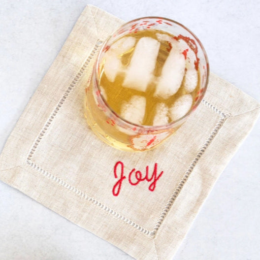 whisky glass on linen coaster embroidered with joy