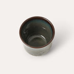 Ceramic cup with brown rim and interior on a white background