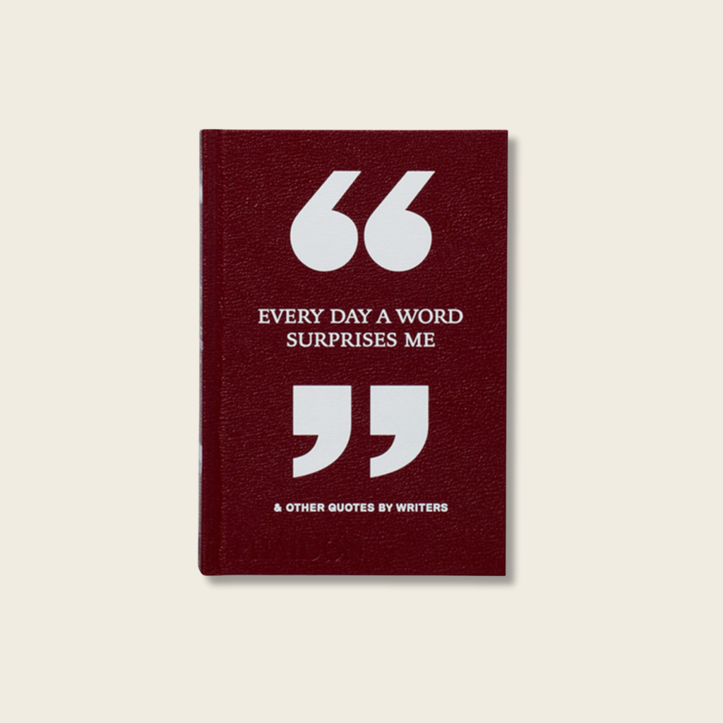 Maroon notebook with white text and quotation marks on a beige background