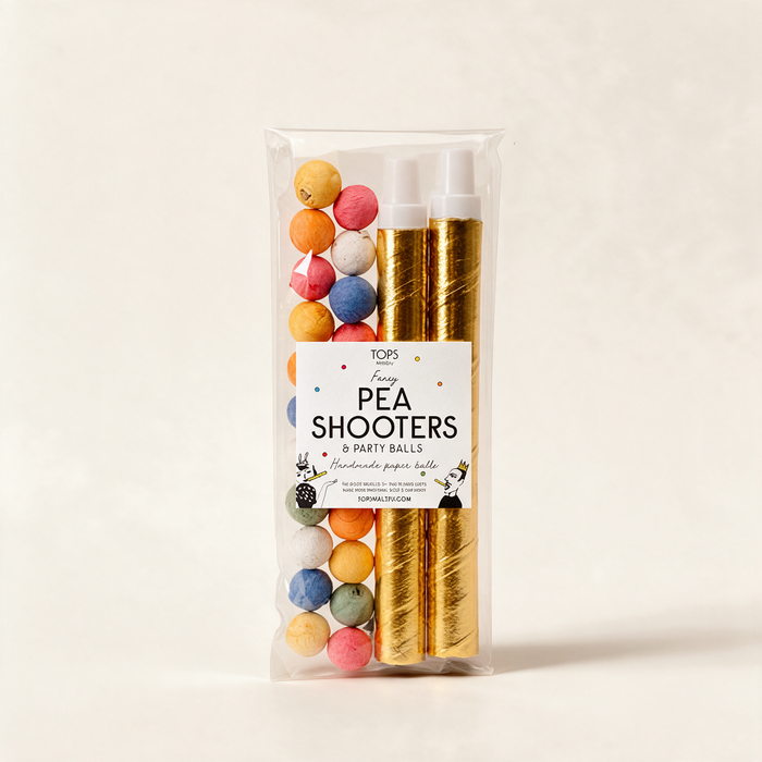 Pair of golden pea shooters with coloured paper balls on a warm cream background
