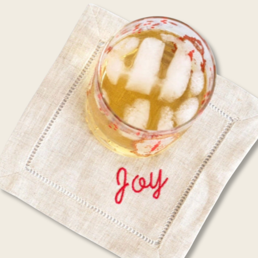 whisky glass on linen coaster embroidered with joy