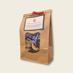 Kraft paper bag with window, containing a blue bag of firelighters, on a beige background.