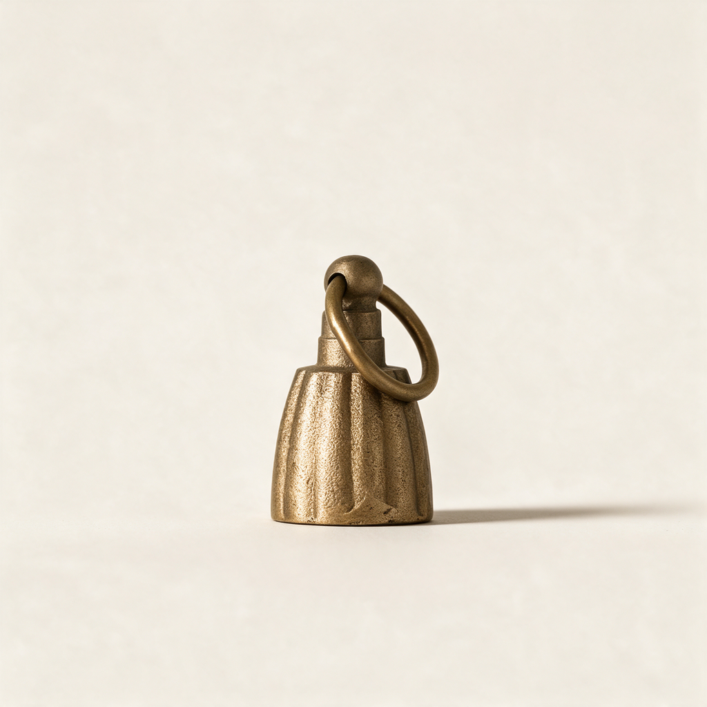 Fluted bell candle snuffer in antique brass on a cream background