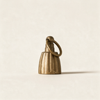 Fluted bell candle snuffer in antique brass on a cream background