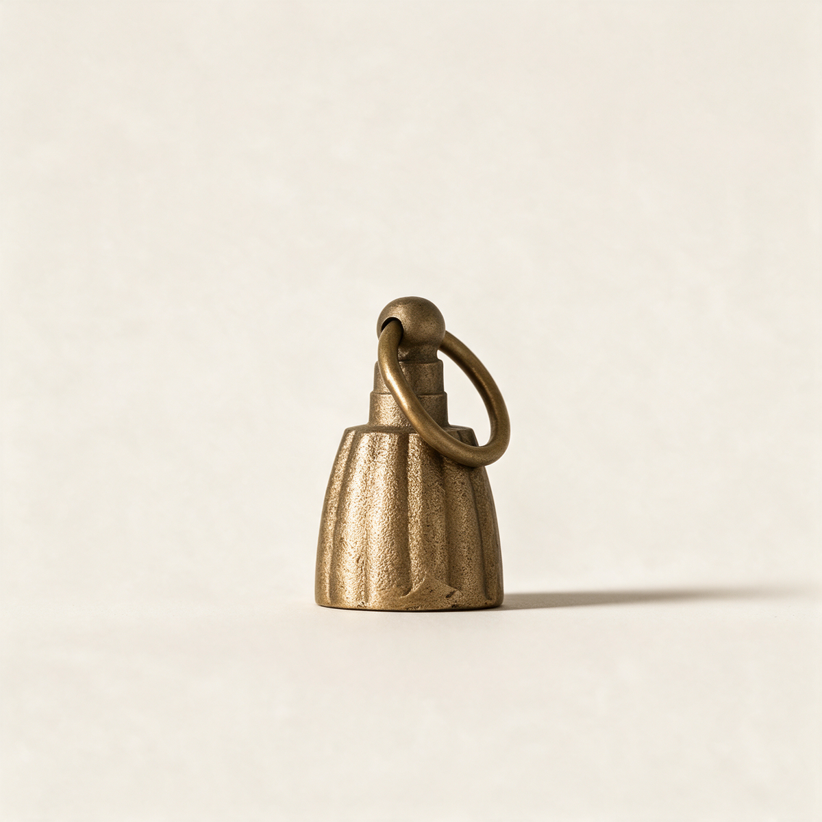 Fluted bell candle snuffer in antique brass on a cream background