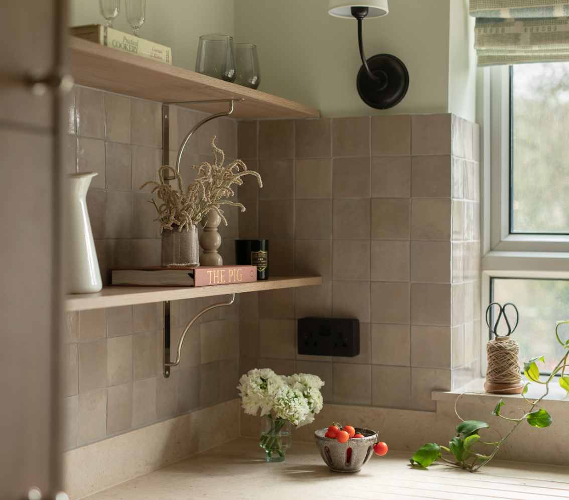 Nestled corner of a room with a shelf, tiled wall, and window.