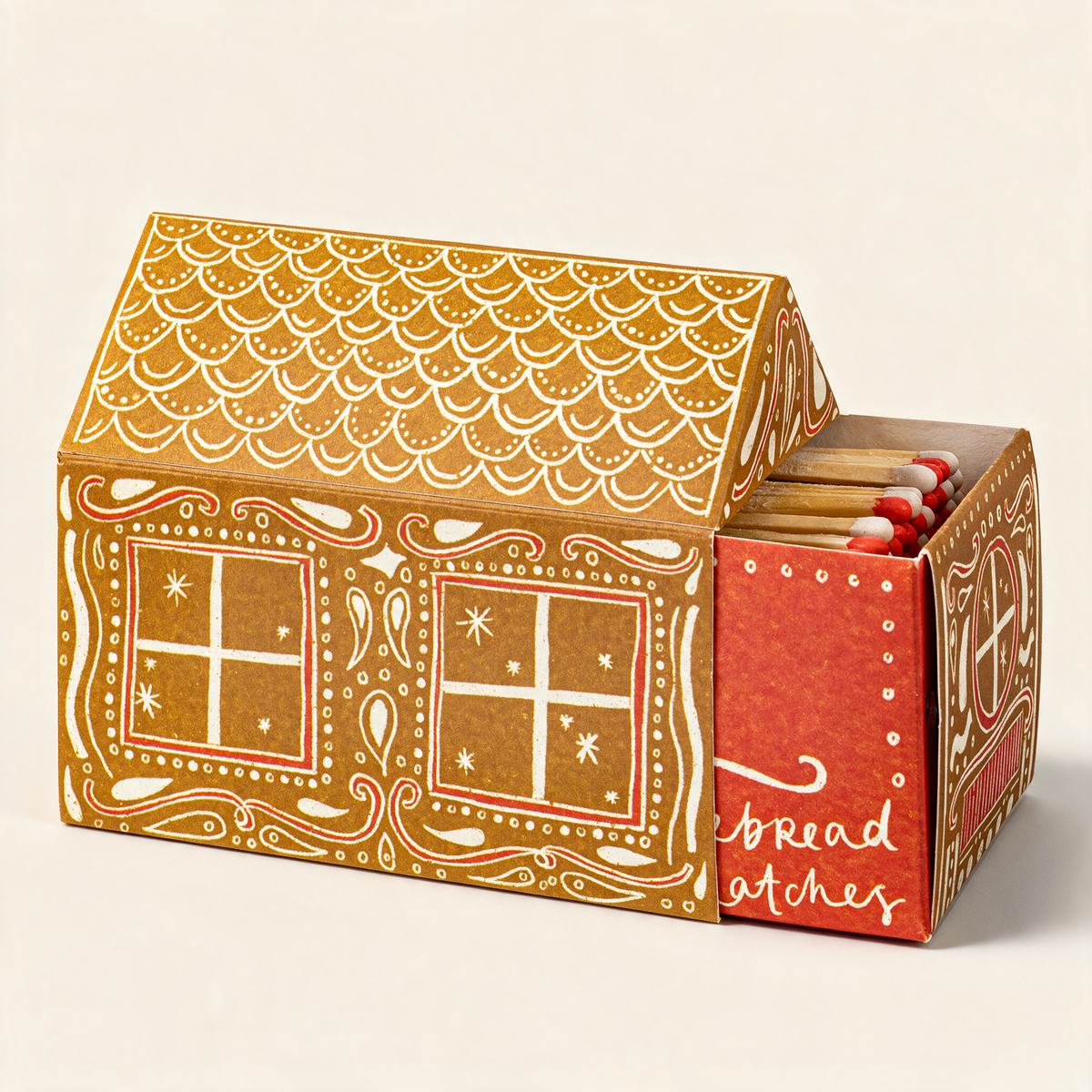Gingerbread house-shaped safety matchbox by Archivist, illustrated gingerbread house with a red door, on a cream background