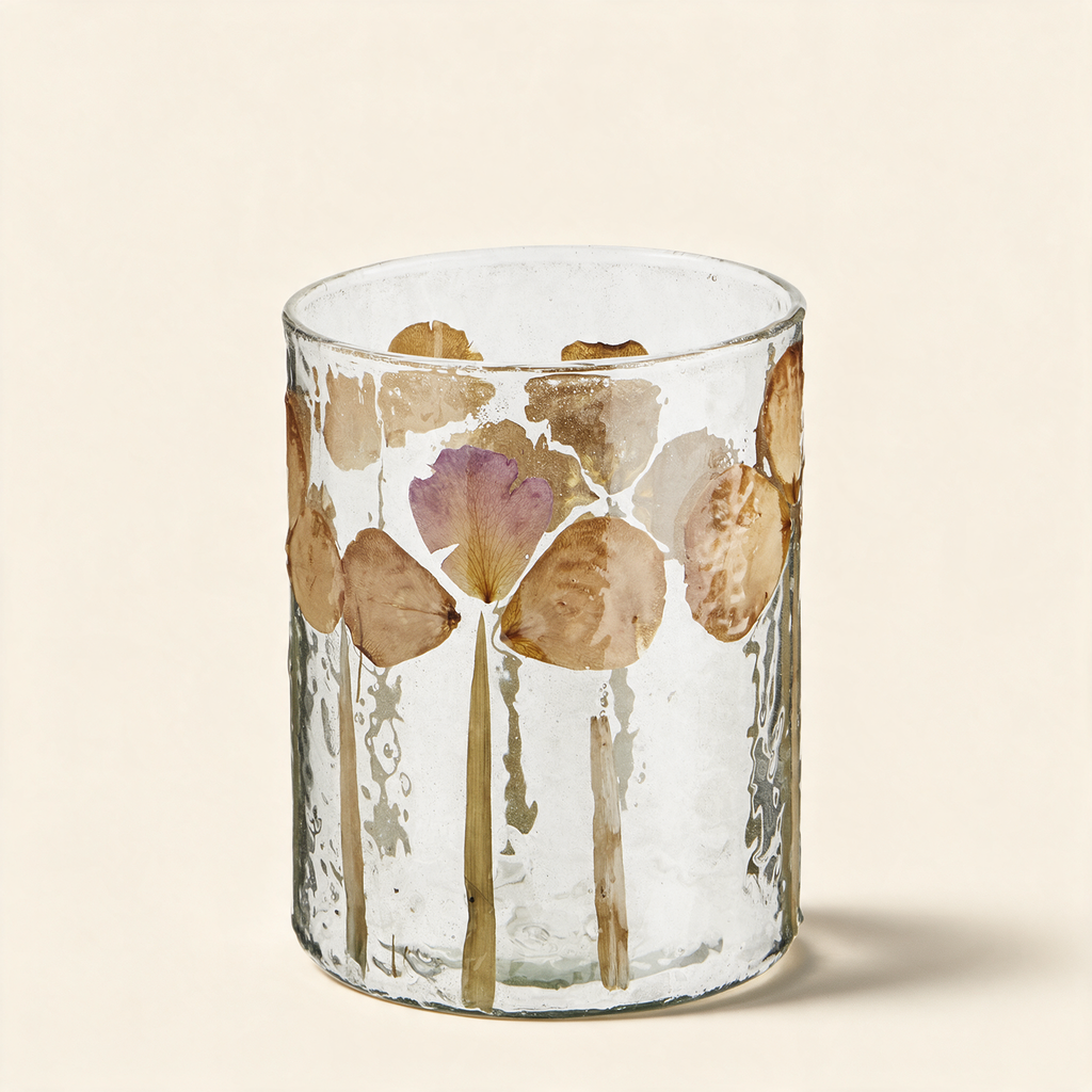 Glass votive with real flower petals set into the glass on a warm cream background
