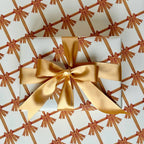A sheet of wrapping paper with a yellow bow design on a beige background, folded loosely.