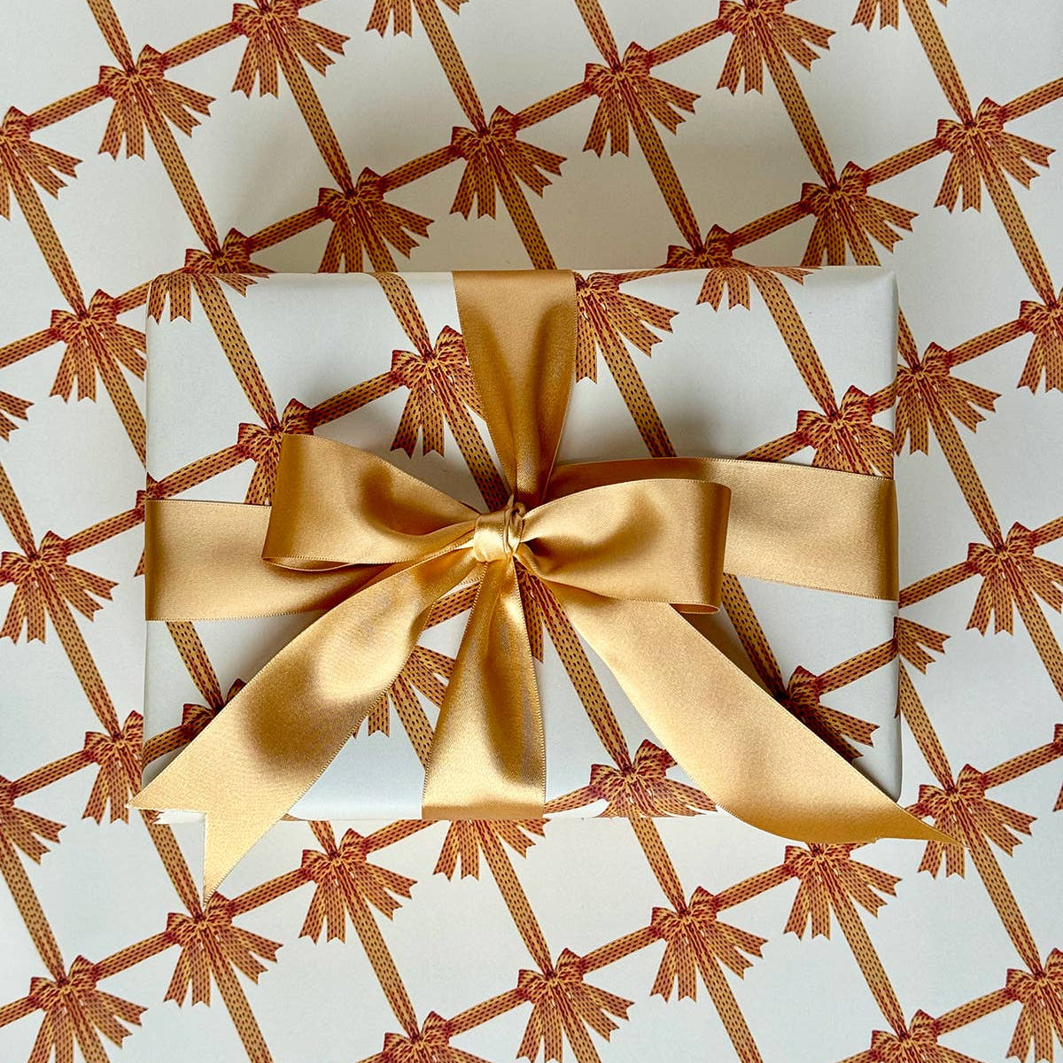 A sheet of wrapping paper with a yellow bow design on a beige background, folded loosely.
