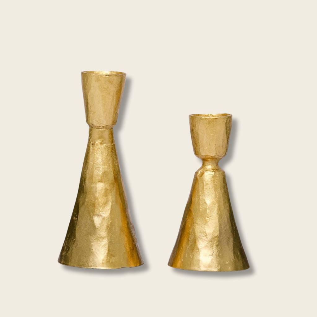 Two gold candle holders on a beige background