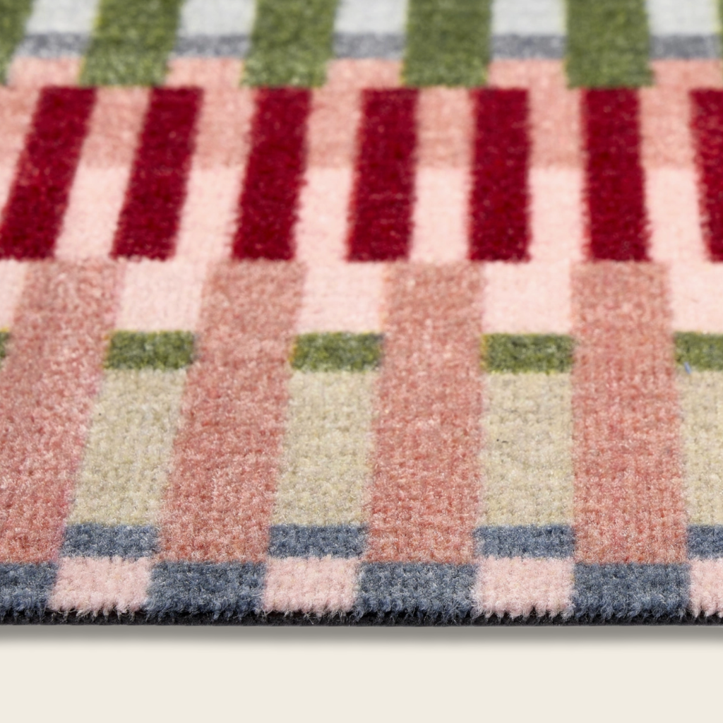Close-up of a multicolored checkered rug with red, green, pink, and blue patterns.