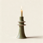 Green stoneware candlestick with a pink rim, on a cream background