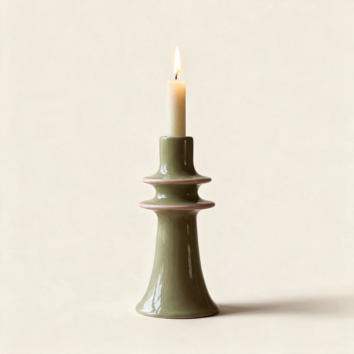 Green stoneware candlestick with a pink rim, on a cream background