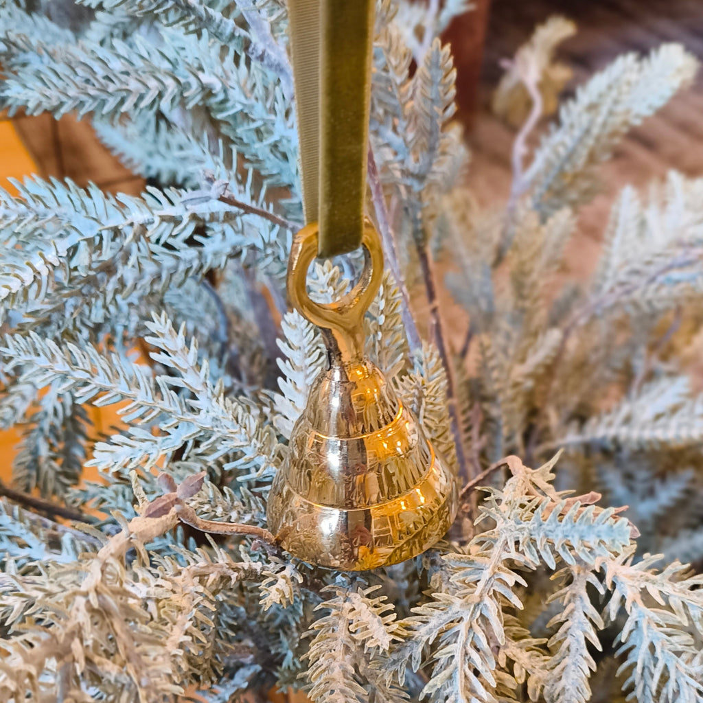 Decorative gold bell hanging on a branch with a blurred background