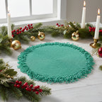 Round green woven mat with fringed edge on a light blue background