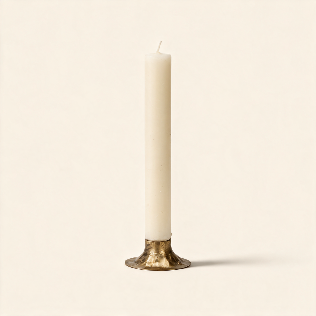 Hand forged iron candle holder with a tulip cup in antique brass on a warm cream background