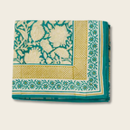 folded printed fabric with flowers and a border on a beige background