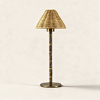 Cordless table lamp with a wicker shade and engraved metal base on a cream background