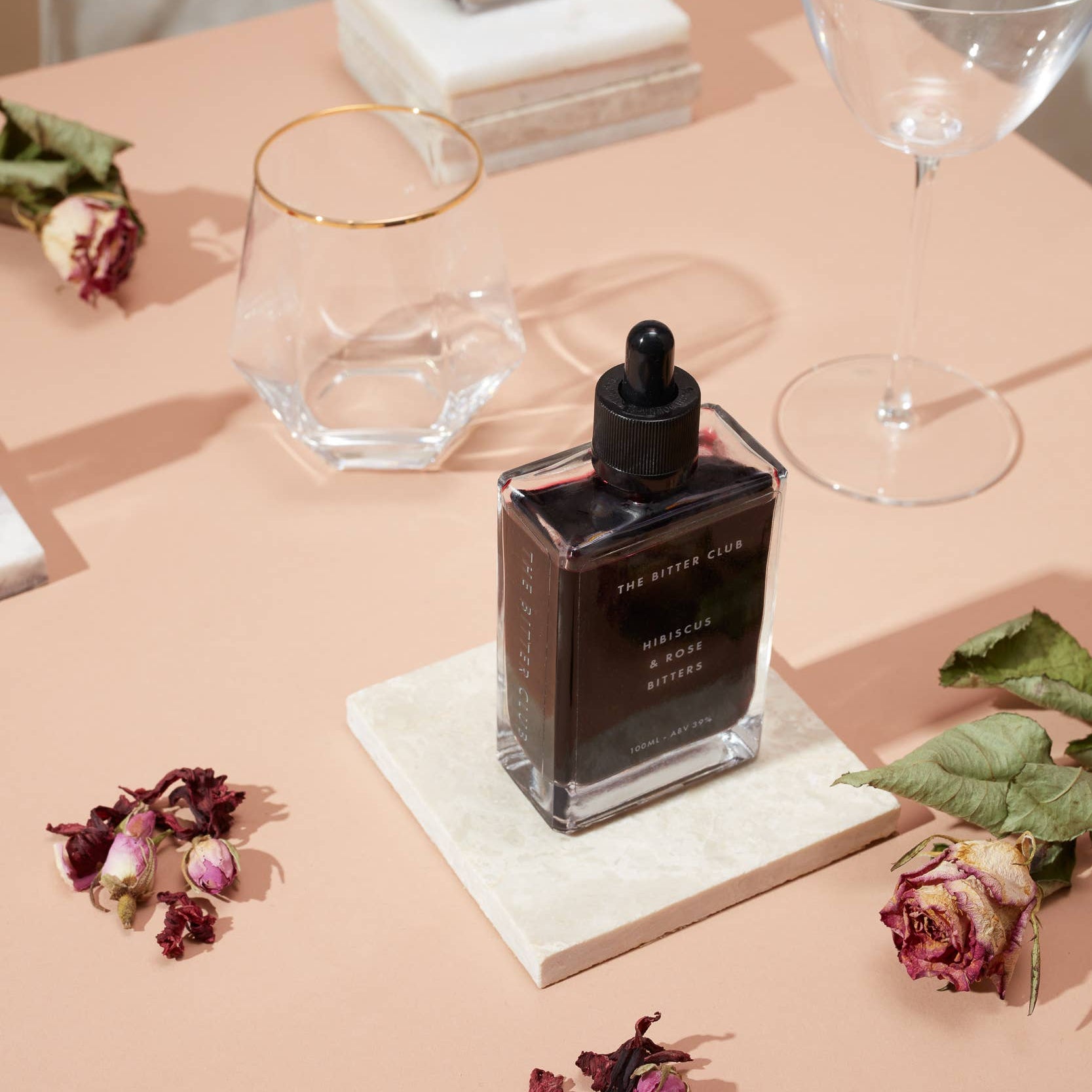 Two bottles of ink on a table with flowers and glasses