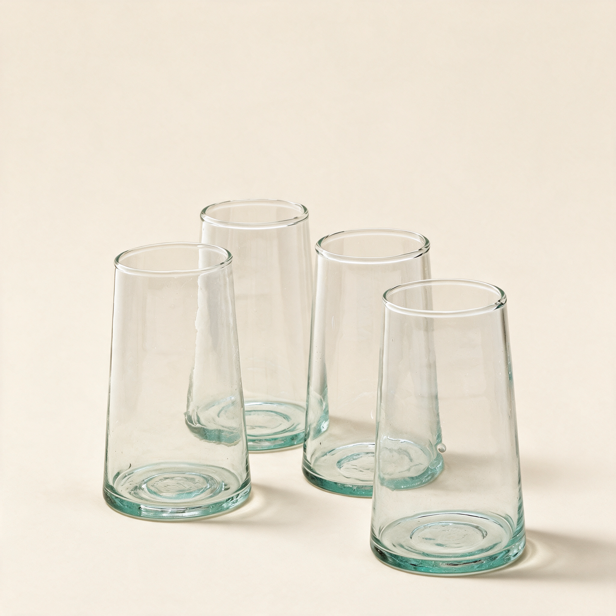 Set of four highball glasses in recycled glass on a cream background